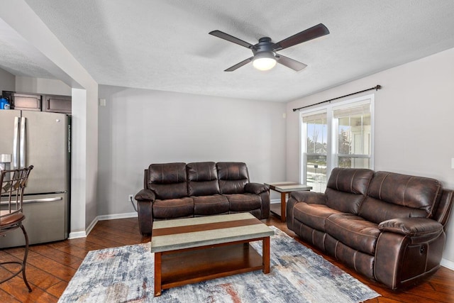 living room with ceiling fan, a textured ceiling, and dark hardwood / wood-style flooring