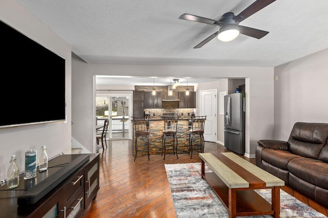 living room with ceiling fan, dark hardwood / wood-style floors, and a textured ceiling