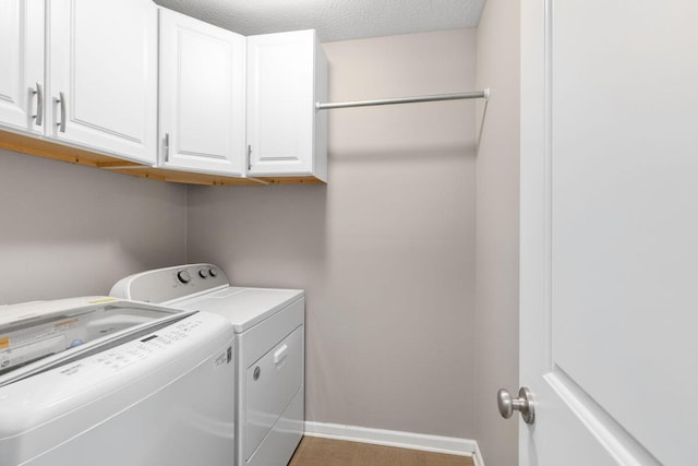 washroom with cabinets, washing machine and clothes dryer, and a textured ceiling