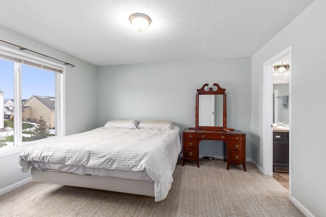 carpeted bedroom featuring ensuite bathroom and a textured ceiling