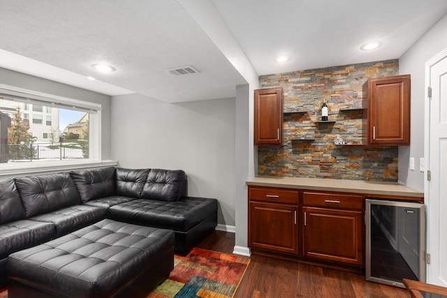 living room featuring dark hardwood / wood-style floors, bar, wine cooler, and a textured ceiling