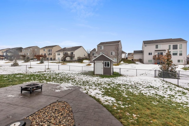 yard covered in snow with a shed and a fire pit