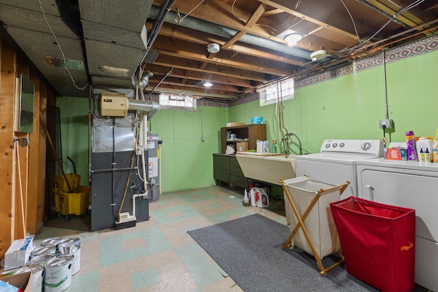 basement featuring washing machine and dryer, gas water heater, and sink