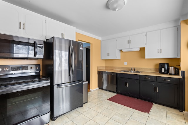 kitchen with sink, light tile patterned floors, white cabinets, and appliances with stainless steel finishes