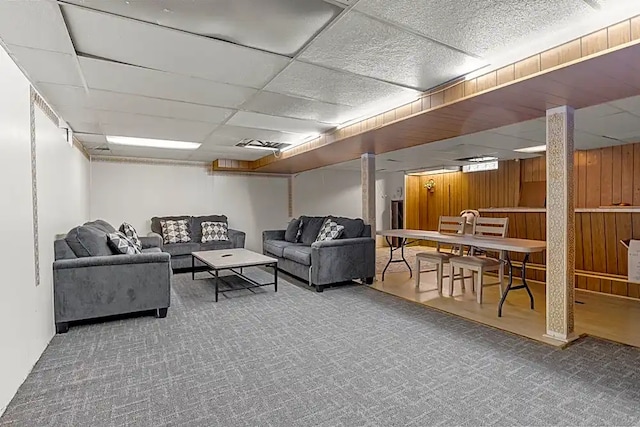 carpeted living room with a paneled ceiling and wood walls