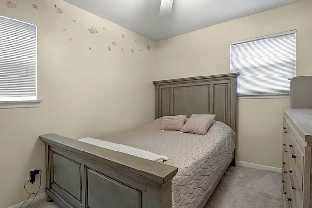 bedroom with ceiling fan, light colored carpet, and multiple windows