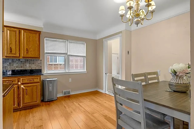 kitchen with ornamental molding, light hardwood / wood-style floors, decorative backsplash, and a notable chandelier