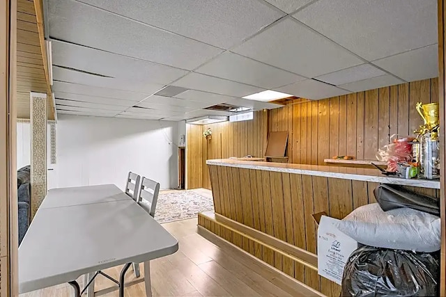 bar with wood-type flooring, a paneled ceiling, and wood walls