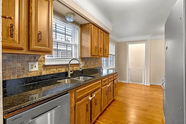 kitchen featuring dishwasher, sink, dark stone countertops, and backsplash