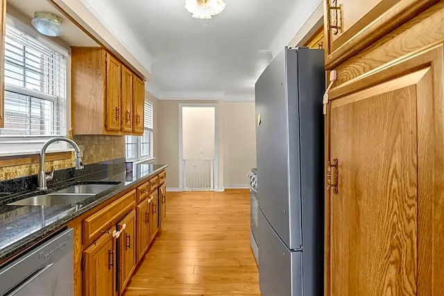 kitchen featuring sink, decorative backsplash, dark stone counters, stainless steel appliances, and a healthy amount of sunlight