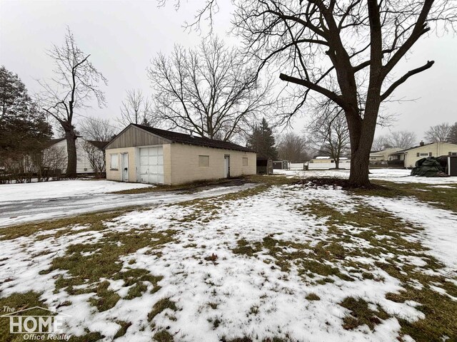 yard layered in snow featuring a garage and an outdoor structure