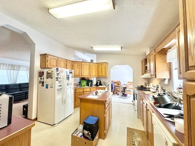 kitchen featuring white appliances, vaulted ceiling, a textured ceiling, and a kitchen island