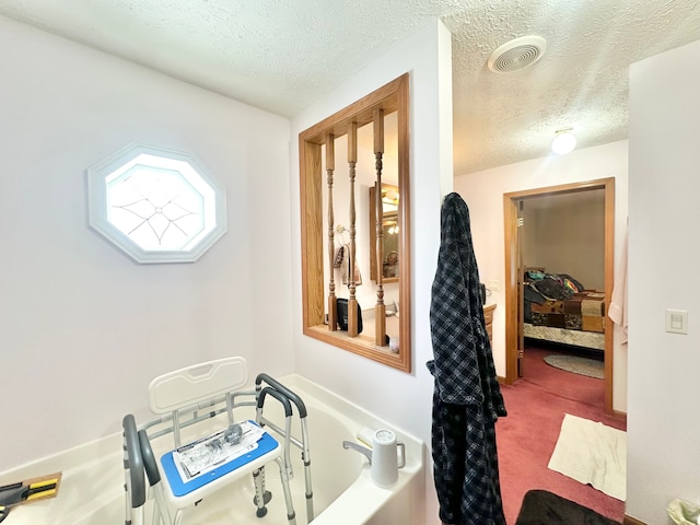 bathroom with a textured ceiling and a tub