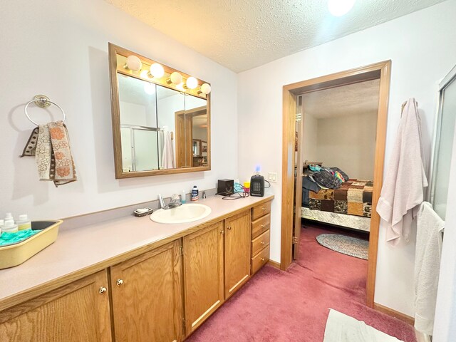 bathroom featuring vanity, a shower with shower door, and a textured ceiling