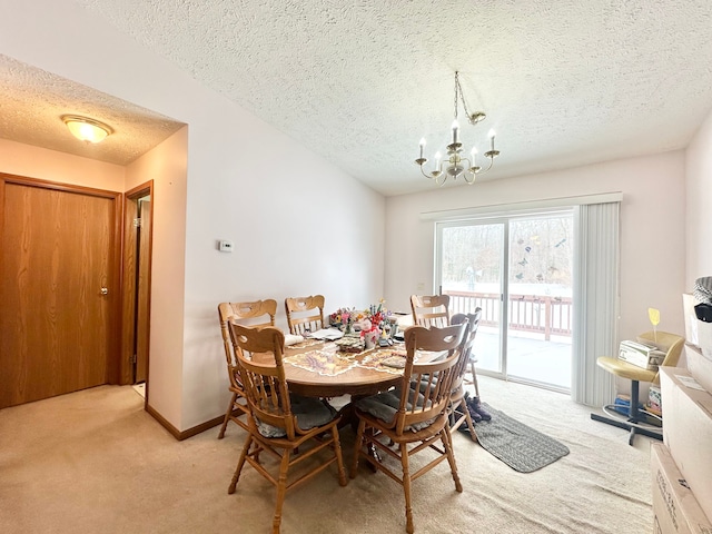 dining area with light colored carpet, a notable chandelier, and a textured ceiling