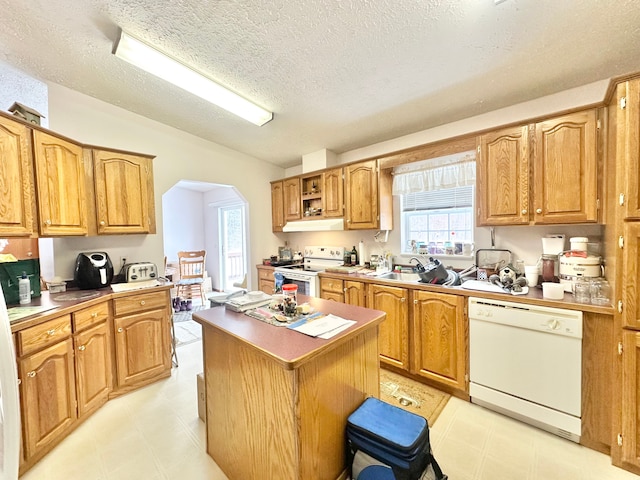 kitchen with a center island, sink, a textured ceiling, and white appliances