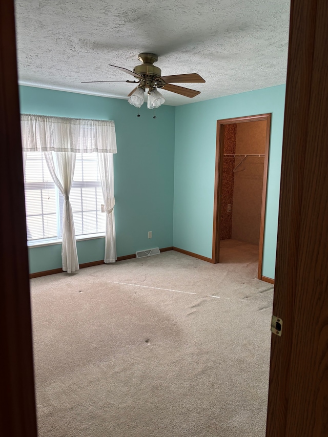 carpeted spare room with visible vents, ceiling fan, a textured ceiling, and baseboards