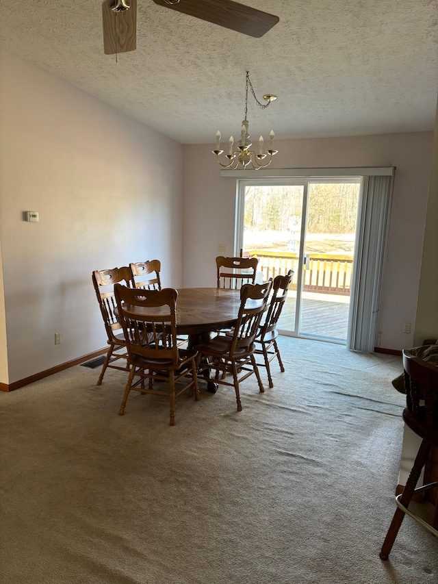 carpeted dining room with a textured ceiling, baseboards, and an inviting chandelier