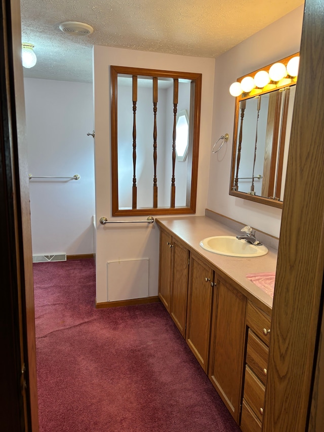 bathroom featuring baseboards, visible vents, a textured ceiling, and vanity