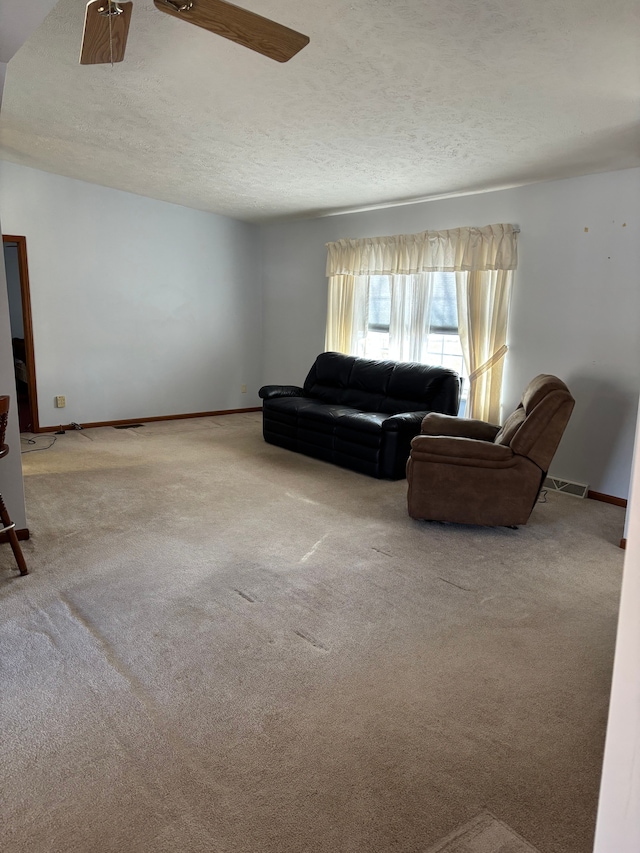 living area with a textured ceiling, carpet flooring, visible vents, and baseboards