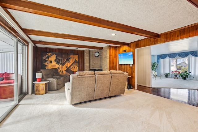 carpeted living room featuring beamed ceiling, a textured ceiling, and wood walls