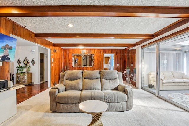 carpeted living room with wooden walls, beamed ceiling, and a textured ceiling