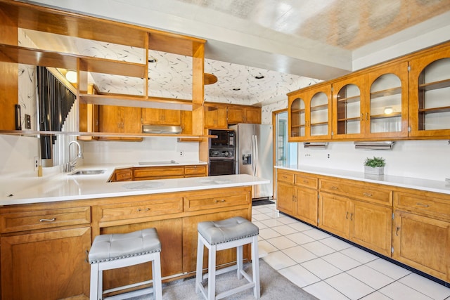 kitchen featuring light tile patterned floors, a kitchen breakfast bar, sink, and black appliances