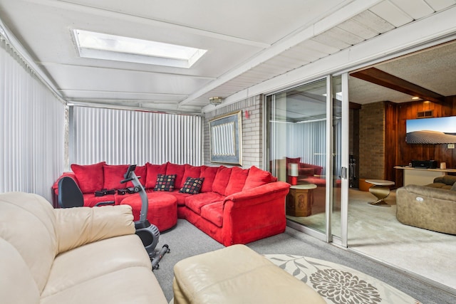 carpeted living room with beamed ceiling and a skylight