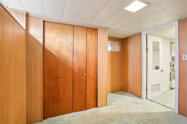 hall with light carpet and wood walls