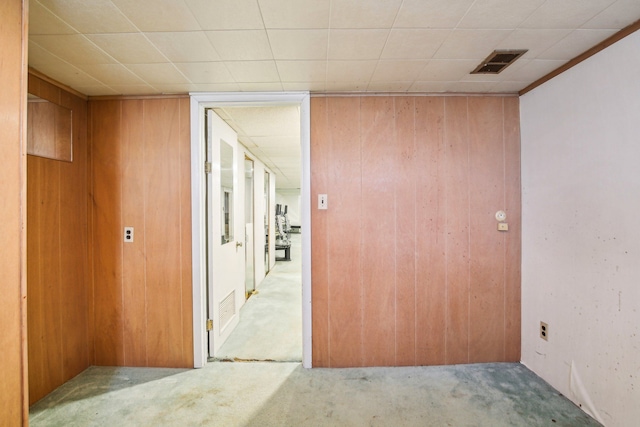 hallway featuring wooden walls and light carpet