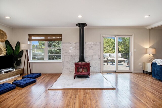 living room with hardwood / wood-style flooring, ornamental molding, and a wood stove