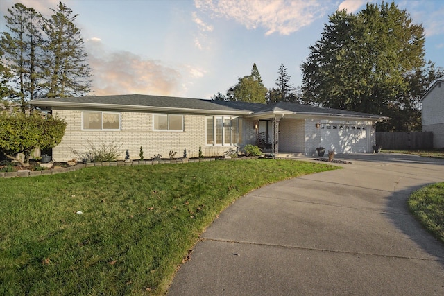 ranch-style house with a garage and a lawn