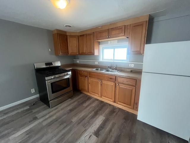 kitchen with white fridge, sink, stainless steel gas range, and dark hardwood / wood-style floors