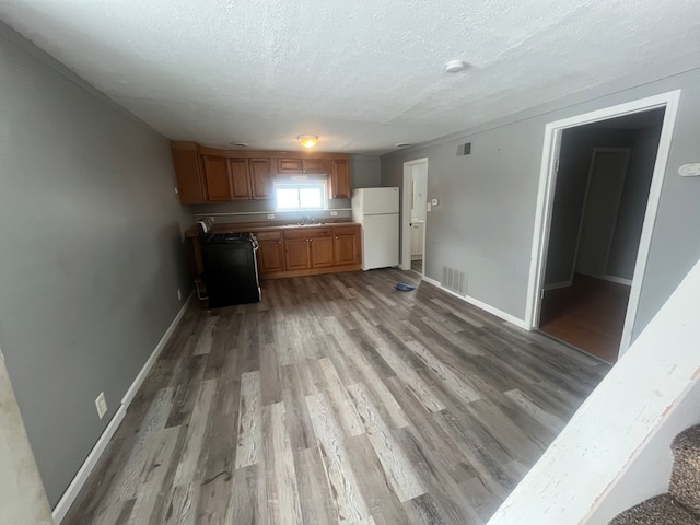 interior space with sink, range, a textured ceiling, light hardwood / wood-style flooring, and white refrigerator