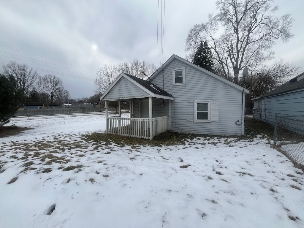 snow covered back of property with a porch