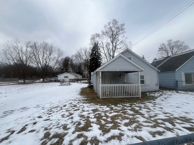 snow covered back of property featuring a porch