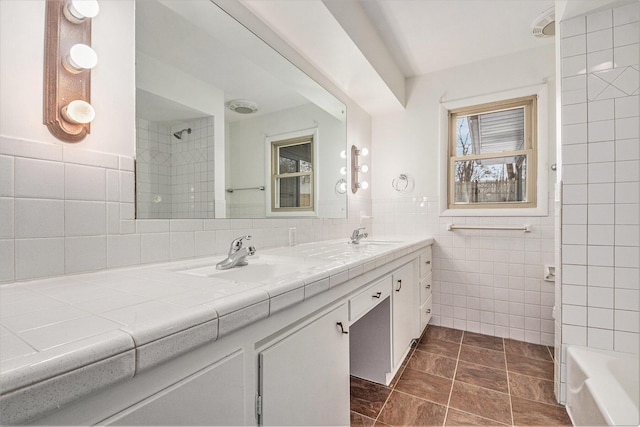 bathroom with tile walls, vanity, and tiled shower / bath