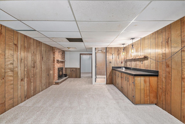 bar with a paneled ceiling, light colored carpet, a fireplace, and wooden walls