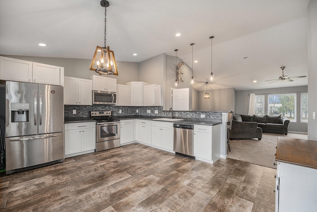 kitchen featuring sink, white cabinetry, stainless steel appliances, tasteful backsplash, and decorative light fixtures