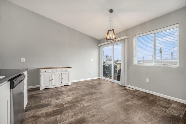 unfurnished dining area with lofted ceiling, dark hardwood / wood-style floors, and an inviting chandelier