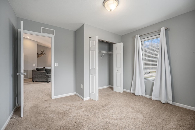 unfurnished bedroom with light colored carpet and a closet