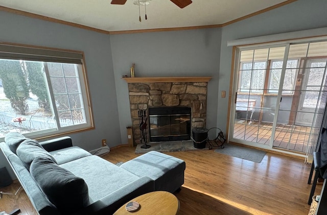 living room with crown molding, wood-type flooring, a fireplace, and plenty of natural light