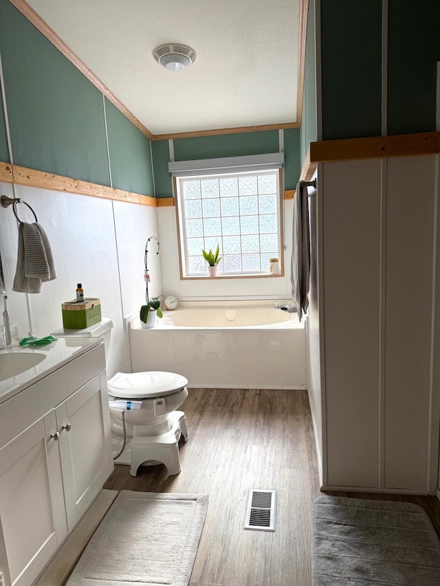 bathroom with a tub to relax in, toilet, a textured ceiling, vanity, and hardwood / wood-style floors