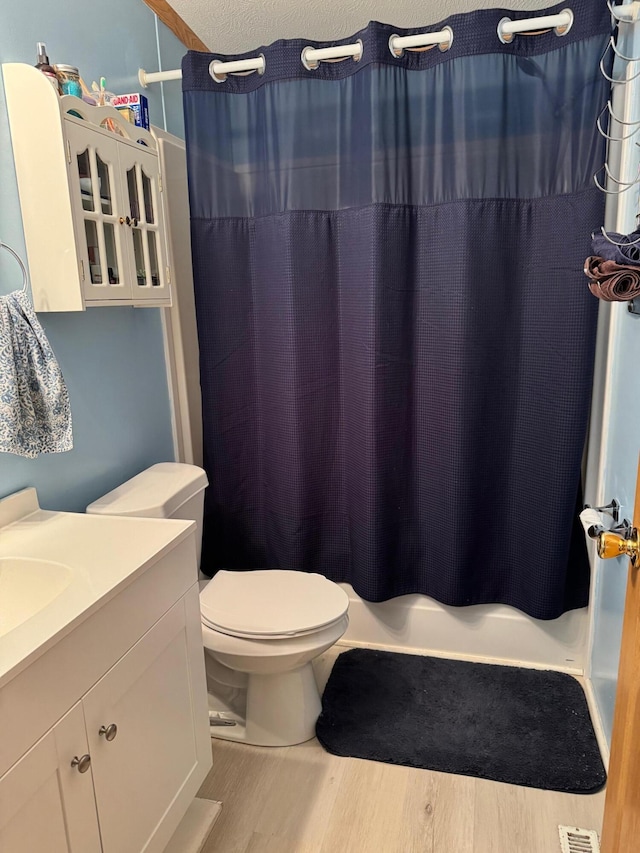 bathroom with a shower with curtain, wood-type flooring, vanity, and toilet