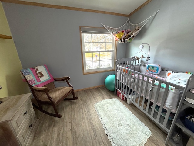 bedroom featuring crown molding, wood-type flooring, and a crib