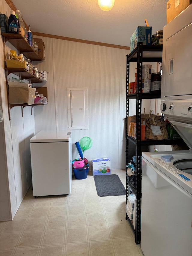 laundry area with stacked washer and clothes dryer and electric panel