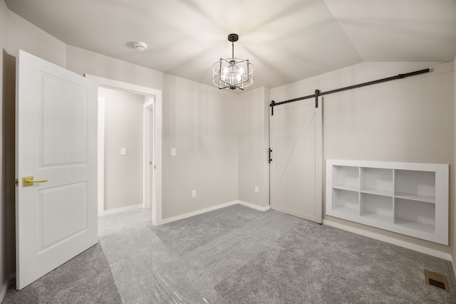 empty room with a notable chandelier, lofted ceiling, a barn door, and carpet