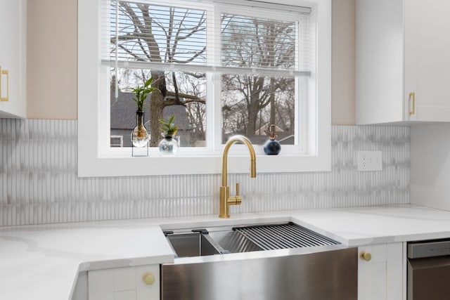 interior details featuring white cabinetry, sink, and light stone counters