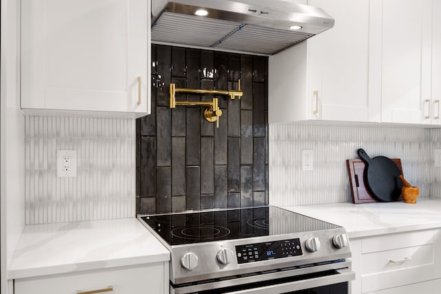 kitchen with stainless steel range with electric cooktop, white cabinetry, tasteful backsplash, light stone counters, and range hood