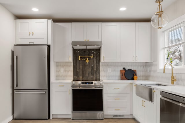 kitchen featuring pendant lighting, appliances with stainless steel finishes, decorative backsplash, and white cabinets